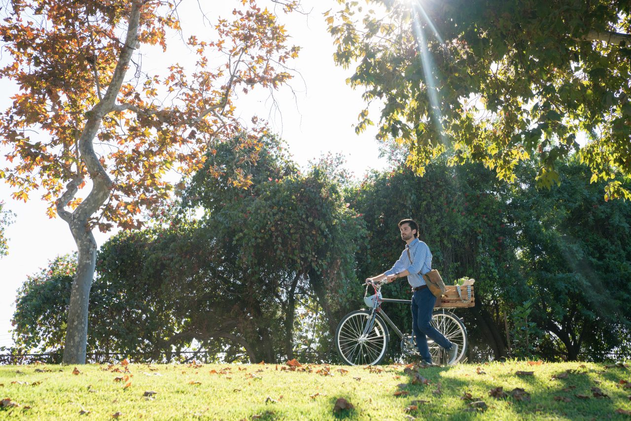 Man pushing a bike in the park