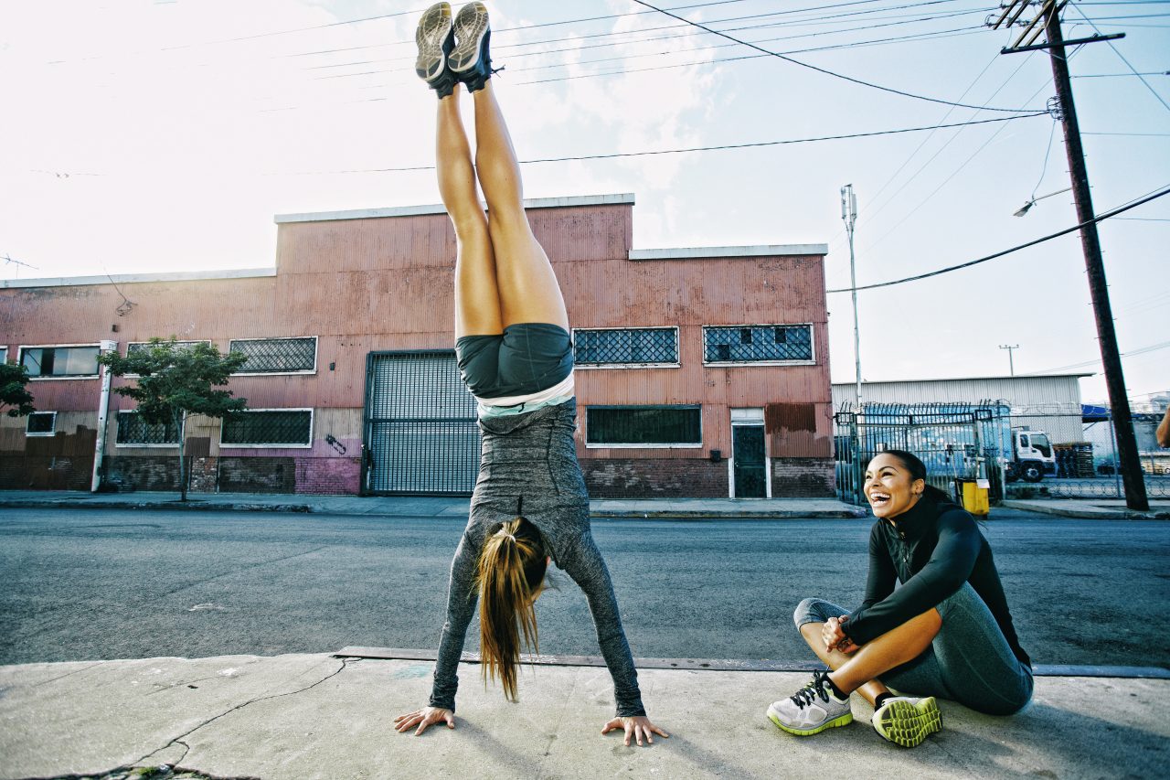 Athlete doing handstand on sidewalk