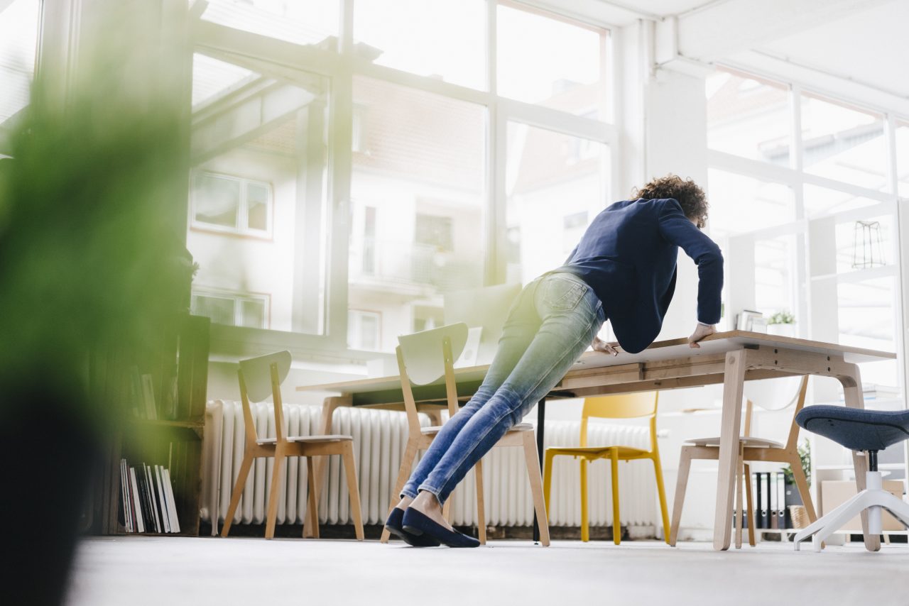 Businesswoman in office doing push ups on desk