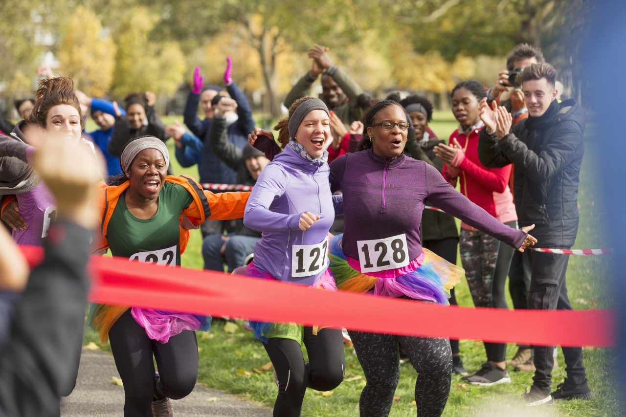 Enthusiastic female runners in tutus nearing finish line at charity run